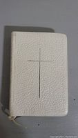 Front view of pocket Bible showing white textured cover with cross design