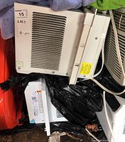 Photo showing two window air conditioners stacked together, one clearly a GE with beige horizontal vents, another partially covered