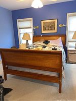 Full view of the Thomas Moser wooden bed showing headboard and footboard with bedding on top in a blue painted room.