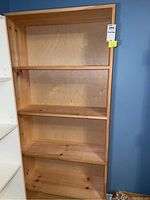 Front view of a wooden bookcase showing all four shelves and overall condition.