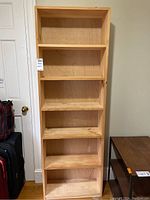 Front view of tall pine wood bookcase with six shelves, showing natural wood with visible grain and knots.