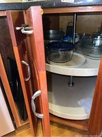 Open cabinet with visible glass mixing bowls and kitchen items on carousel shelf