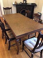 Overview of 6 wood dining chairs around dining table, showing design and seat cushions.