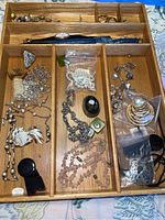 Full view of wooden tray containing assorted jewelry items including watch, brooches, necklaces, earrings