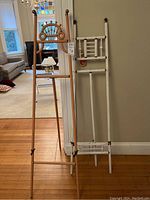 Two wooden easels standing side by side against a wall with a couch and stair rail in background.