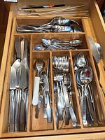 Full view of wooden drawer organizer filled with assorted flatware and chopsticks