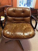 Front view of brown leather Knoll office chair showing worn leather seat with cracks and creases, and black metal armrests with wood accents.