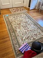 Large floral patterned rug measuring 4'x6' in earth tone colors indoor on hardwood floor.