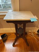Full view of the wood side table with white marble stone top against wall, showcasing the tabletop and base.