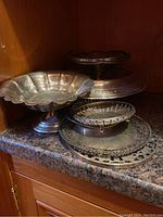 Overview of five sterling serving pieces on countertop