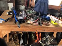 Overview of work table top and items underneath showing assorted tools, hardware, and cords.