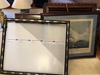 Group of stacked frames on carpet, front frame contains white protective sheet