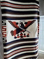 Full view of the large vintage blanket with central eagle motif, horizontal stripes, and geometric border pattern.
