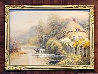 Full view of framed watercolour painting showing cottage, river, cows and frame