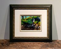 Framed oil painting with dark green and gold detailed frame, showing a forest water scene with rocks and tree trunks.