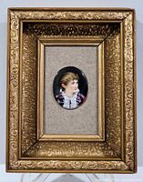 Full view of miniature painting in elaborate gold frame showing decorative edges and oval artwork centered on beige background.