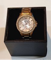 Fossil ladies gold-tone wristwatch in black box, visible crystal bezel and link bracelet.