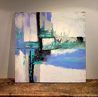 Square canvas abstract oil painting displaying mixed colors and textures on a wooden surface.