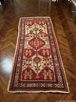 Full view of the rectangular Persian rug on wooden floor, showing overall design and condition.