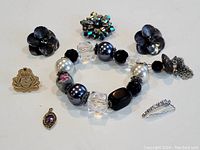 Photo showing the multi-beaded bracelet, black flower clip-on earrings, two small pins, and small rhinestone curved clip accessory.