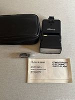 Photo of flash, instruction manual, lens shell accessory, and carrying case.