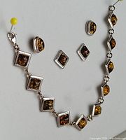 Full view of necklace and earrings showing the silver frames and amber stones in the set.