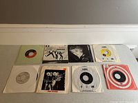 Top view of 8 collectible 7 inch vinyl albums in sleeves, showing a variety of artists and labels