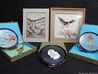 Four framed Asian art pieces on black background showing silk embroidery and feather art combined with wood frames.