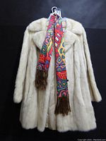 Front view of the classic light beige mink fur coat, hanging with a colorful patterned scarf for display.