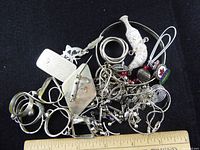 Top view of mixed metal jewelry pieces and trinkets including bracelets, rings, pendants, and chain links.