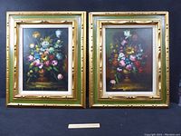 Pair of framed floral oil paintings with green and gold distressed wooden frames shown from the front.