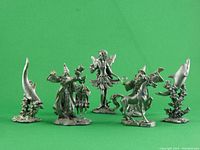 Photo showing five pewter figurines including a fairy, two wizards, a wizard on a unicorn, and two horn-shaped decorative pieces.