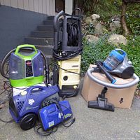 Full view of the cleaning appliances together showing the Dirt Devil vacuum, Little Green ProHeat cleaner, Karcher pressure washer, and additional vacuum accessories.