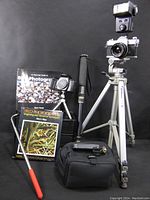 Entire lot displayed showing Canon AE-1 camera on tripod, Pentax camera, camera bags, cleaning tool, and photography books.