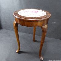 Full side view of vintage end table with porcelain top and curved legs.