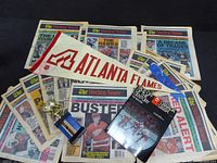 All items laid out: 12 Hockey News magazines, hockey book, Atlanta Flames pennant, small trophy