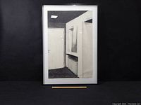 Framed charcoal drawing showing an interior architectural scene including a door, radiator, and artwork on the wall.