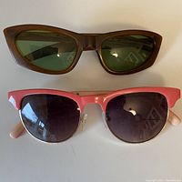 Top-down view of both pairs of sunglasses: dark brown Cool Ray Polaroid pair and peach-colored Anne Taylor pair.