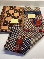 Two folded pieces of Liberty wool fabric, one with a geometric peach and brown design and the other with blue and beige checkerboard with floral accents.