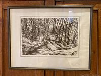 View of the full framed lithograph artwork showing the winter forest scene in black and cream, with visible signature and date.