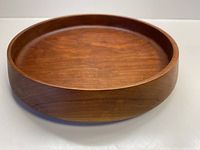 Front angle view of hand turned shallow wooden bowl showing smooth interior and curved edges.