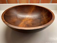 Side angle of the wooden bowl showing the curved profile and finish.