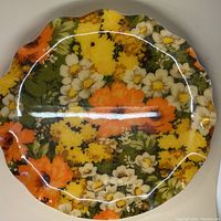 Full view of the circular tray with rippled edge showing multicolored floral fabric under resin coating.