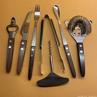 Full set of seven stainless steel barware tools with rosewood handles laid out on a surface.
