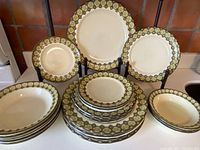 Full set of Franciscan dishes arranged showing various plate sizes and bowls with floral border and creamy mustard background.