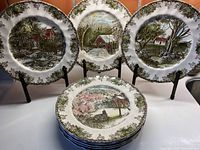 Set of eight Johnson Bros. The Friendly Village dinner plates showing multiple different scenic village designs and ornate ivy grape vine borders.
