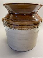 Front view showing cream base, brown glazed upper part with textured spheres and diamonds, wide flared rim.