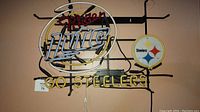 Go Steelers neon sign with yellow neon tubes and Steelers logo attached to black metal frame on wall