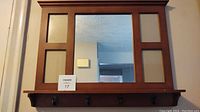 Front view of the wood-framed mirror with hooks and photo inserts showing layout and condition