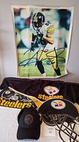 Autographed Pittsburgh Steelers vinyl poster, two hats including circular logo cap and large helmet replica hat, and two pennants arranged on a surface.